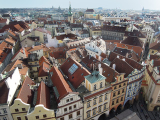 Fototapeta na wymiar Panoramic view on Prague roofs of buildings surrounding Old Town Square from top of Old Town Hall tower. Tower is one of most popular places for tourists to make photos of Prague, Czech Republic