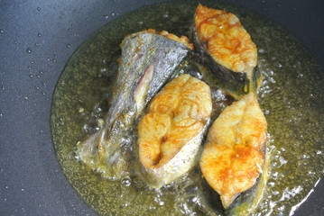 Spanish mackerels fish cut into thick slices and fried using hot cooking oil. The slices of fish...