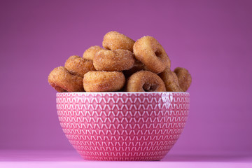Cinnamon Sugar Mini Donuts in a bowl on a pink background