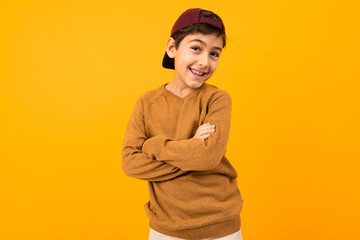european funny teenager boy in casual stylish brown sweater stands arms crossed on a yellow background with copy space