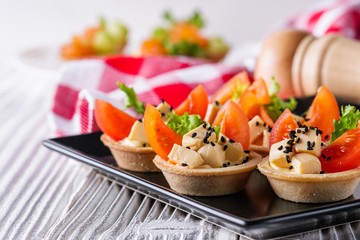 delicious snack tartlets on rustic wooden background