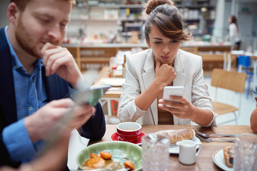 business people  at lunch, not talking, worried, after covid, distracted from each other by cell phones. issues, recessions, problems.