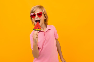 Handsome boy in pink t-shirt smiles and gesticulates isolated on orange background