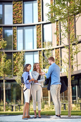 Fototapeta premium group of young business people talking in front of a building. vertical image with copy cpace