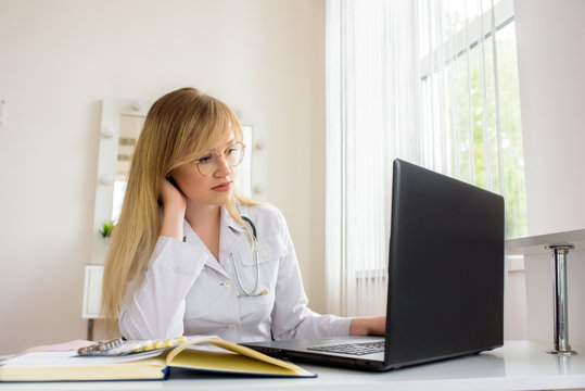 young stressed woman doctor sitting in modern office.tired doctor at the computer. online consultation.