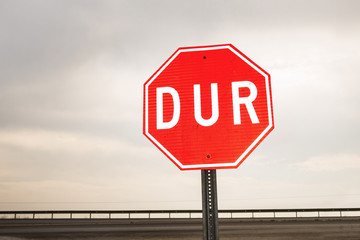 International hexagonal traffic sign 'Stop' (written in Turkish) on cloudy sky background