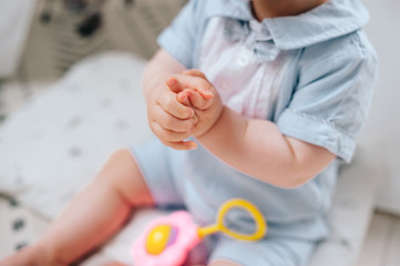 A small child is sitting on the floor on the carpet, the child is wearing pajamas. Next to the child is a colored toy.