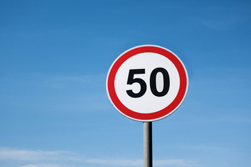 International traffic sign 'Speed limit' (to 50 km or miles per hour). Clear blue sky is on ...