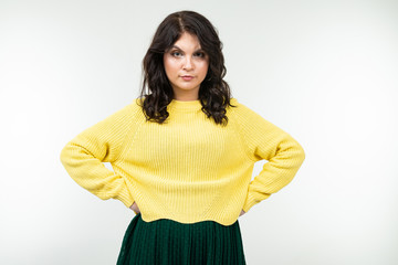 offended girl in a yellow sweater and green skirt on a white background