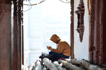 Fototapeta premium Young boy concentrated on his phone in Durbar Square, Kathmandu.