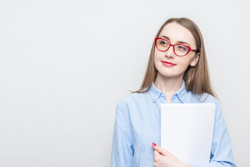 Beautiful student in red glasses looks thoughtfully to the side, portrait, white background, copy space