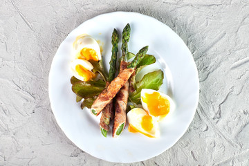 Fresh organic asparagus baked with bacon in the oven, with poached egg. Close up, top view