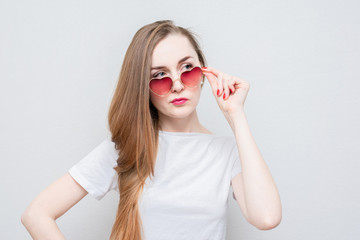 Fatal woman takes off her heart-shaped glasses and looks at someone in the side, portrait, white background