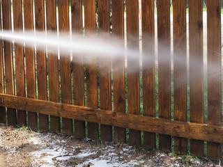 Sanitary cleaning private territory and wooden fence with equipment pressure washer, containing a disinfectant during infection of corona virus covid-19