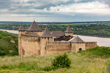 Khotyn Fortress castle in Ukraine, river on a background of dark clouds on a cloudy windy day in summer. Horizontal orientation.