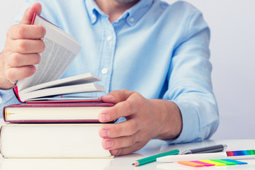 Concept of education. Student guy with stack of books, man's hands, cropped image, closeup