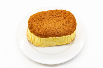 Sponge cake is on white plate and white background .Sponge cake is a light cake made with eggs, flour and sugar, sometimes leavened with baking powder.