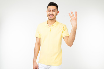 joyful man in a yellow shirt shows three fingers on a white isolated background