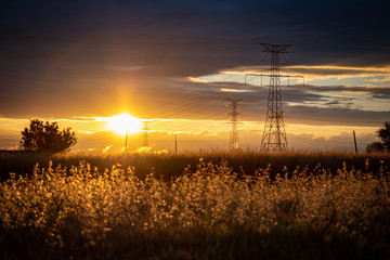 Obraz premium sunset landscape with high voltage electricity pylons