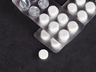 Round white medical tablets in a package and one pill on a gray background closeup. Antipyretics...