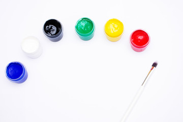 Cans of different colors gouache paints and artist brush, white background, copy space, 16:9