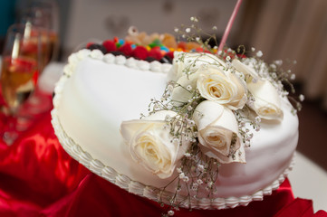 wedding and birthday cake decorated with chocolate bonbons, colorful cookies and strawberries, with white natural flowers