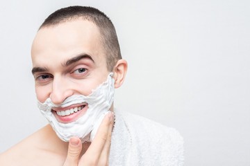 Cheerful man with shaving foam on his face, white background, copy space