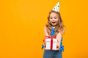 Nice little girl with a birthday party holds a present isolated on white background