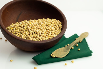 porotos de soja en cuenco de madera con servilleta y chuchara rustica sobre fondo blanco
frescos y...