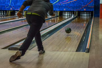 Man playing bowling seen from the back, focus on the ball.