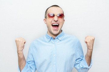 In love man rejoices in victory or good news, guy with heart-shaped glasses, white background