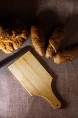 forma de pan casero y pan con cereales y tabla de cortar con cuchillo dentado.