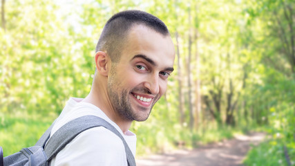 Cheerful traveler stands in the forest and smiles, close up, toned, 16:9