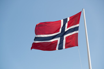 Norwegian national flag in strong wind, sunny, blue sky
