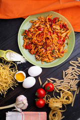  italian pasta with tomatos and herbs on dark wooden table. italian pasta recipe.  flat lay