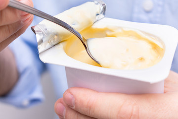 Man's hand holding yogurt while eating, closeup