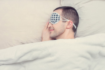 Concept of healthy sleep. Handsome man with dressing for sleep sleeping in bed, closeup, top view