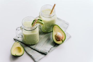 creamy smoothie from avocado and banana in glass cups with paper tubes on a light background. no plastic. healthy food. top view