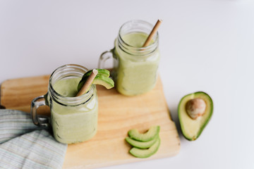 creamy smoothie from avocado and banana in glass cups with paper tubes on a light background. no plastic. healthy food. top view