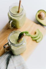 creamy smoothie from avocado and banana in glass cups with paper tubes on a light background. no plastic. healthy food. top view