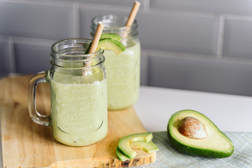 creamy smoothie from avocado and banana in glass cups with paper tubes on a light background. no...