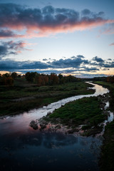 Slow river with dramatic clouds and trees around