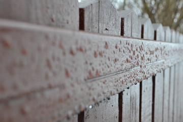 Wet brown wood fence with water drips on it