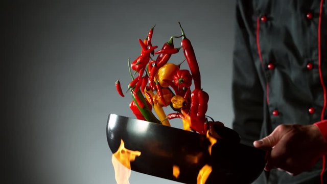 Super slow motion of flying chilli peppers from wok pan, chef closeup. Filmed on high speed cinema camera, 1000 fps.