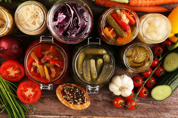 Preserves vegetables in glass jars. Pickled Cucumber, carrot, fermented cabbage and onions on rustic background