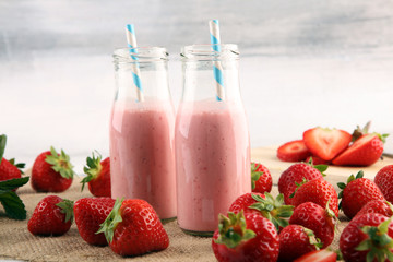 Glass of fresh strawberry shake, smoothie or milkshake and fresh strawberries on table. Healthy food and drink concept