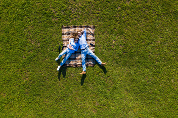 Young couple lying on the grass and looking up in the park. Top view on the lying couple from above