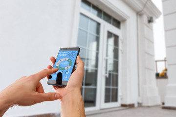 smart house, home automation, device with app icons. Man uses his smartphone with smarthome...