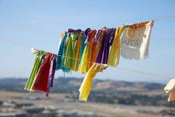Colorful Tibetan Prayer flags hang on lines with blue sky behind, high above small town below 