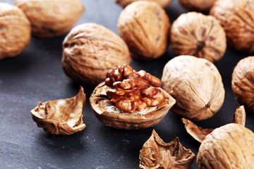 Walnut kernels and group of whole walnuts on rustic old table